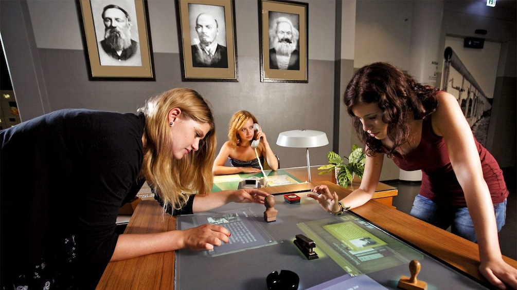 Small group of people interacting with a touchscreen exhibit piece at the DDR Museum in Berlin