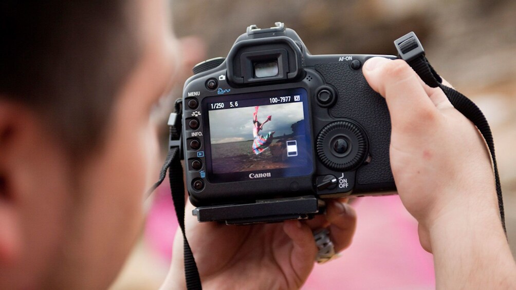 Photographer checking his shot on his camera screen on a beach in Sydney