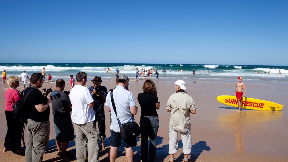 Photography group setting up on a beach with a model dressed as a lifeguard