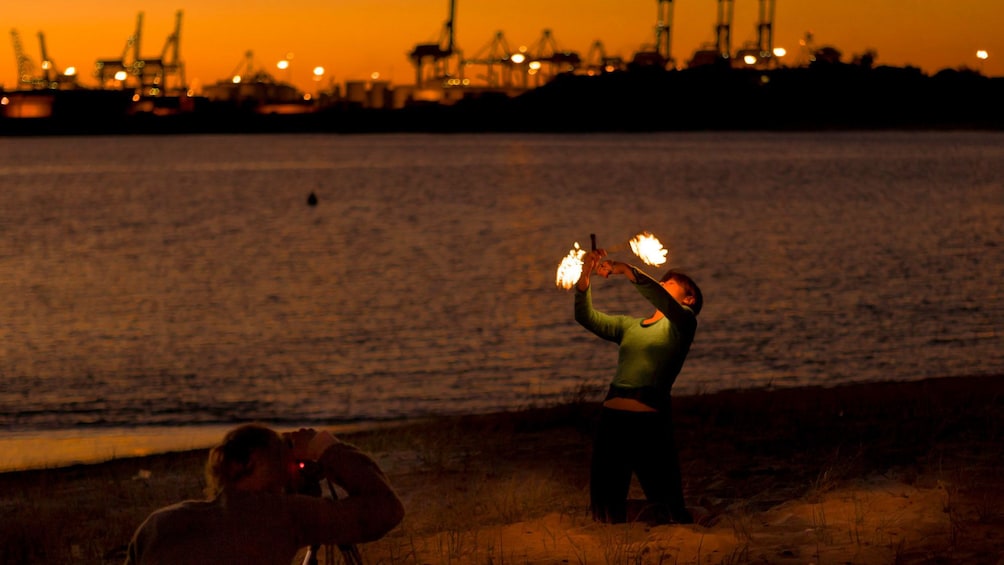 Fire dancer on the shore of Sydney Harbor at sunset