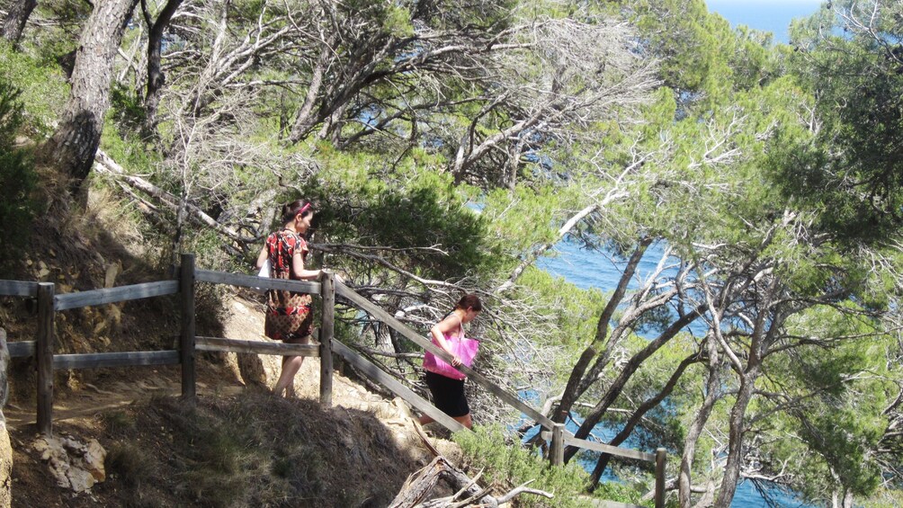 Öppna foto 2 av 5. two women walk down trail near cliff in Barcelona