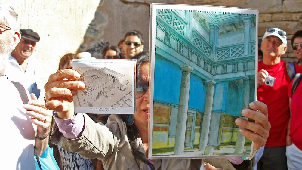 Tour guide showing illustrations of what the ruins originally looked like on Delos