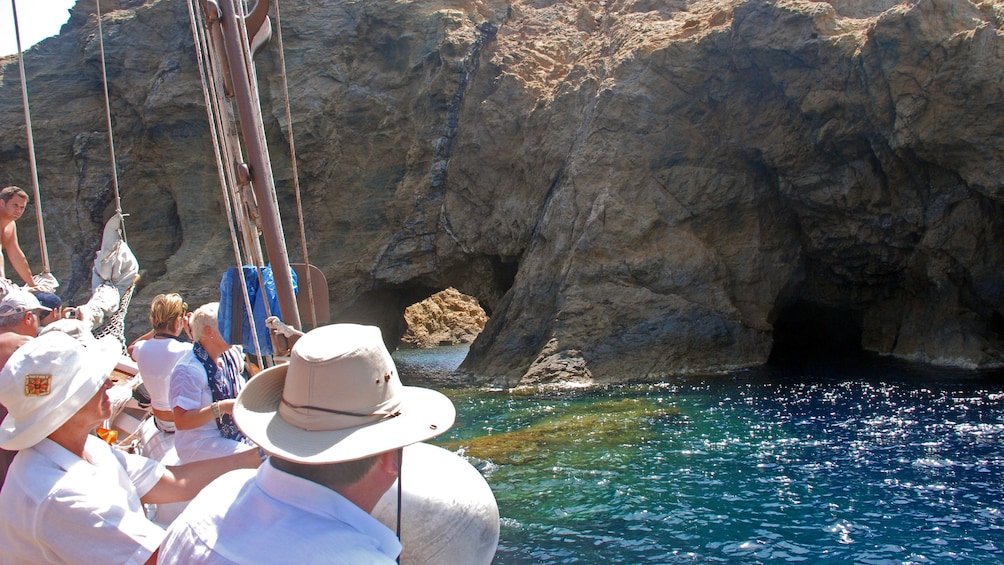 Sailboating tour group looking at caves and rock formations on the coast of Dragonissi