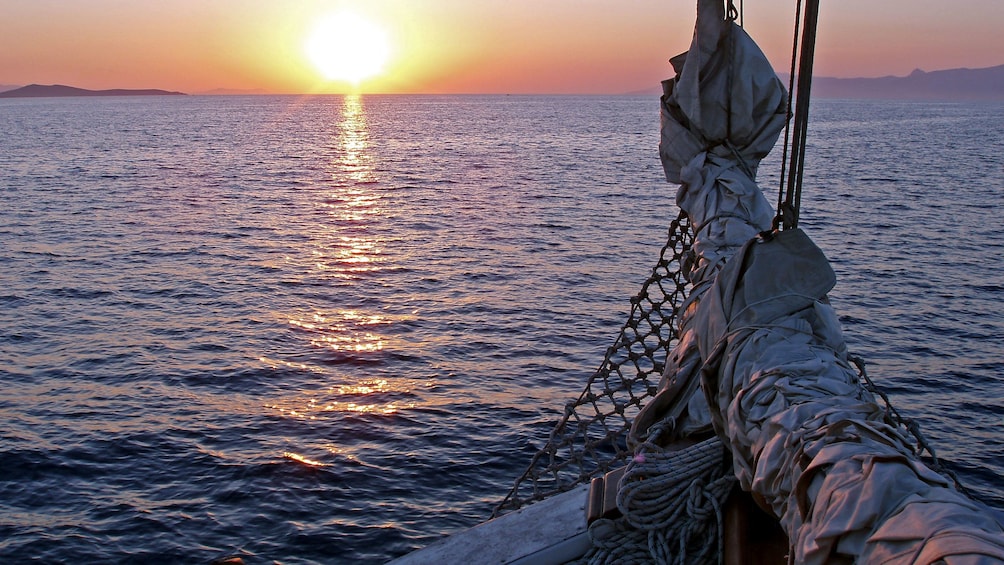 View of the sunsetting over the water from a sailboat in Mykonos