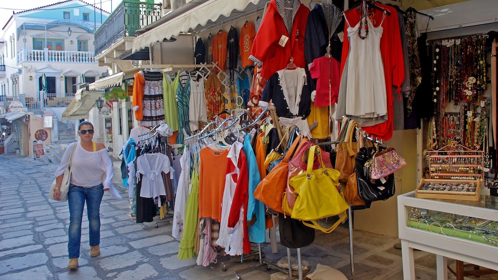 Woman shopping for clothes and jewelry at an open-air market in Tinos