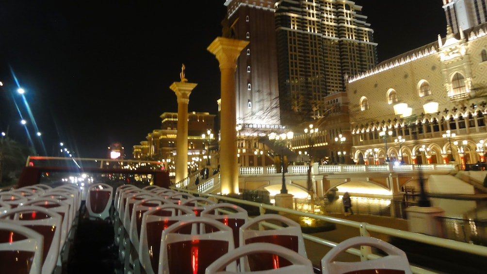 Show item 3 of 5. Tour bus driving past the Venetian Hotel at night in Macau.