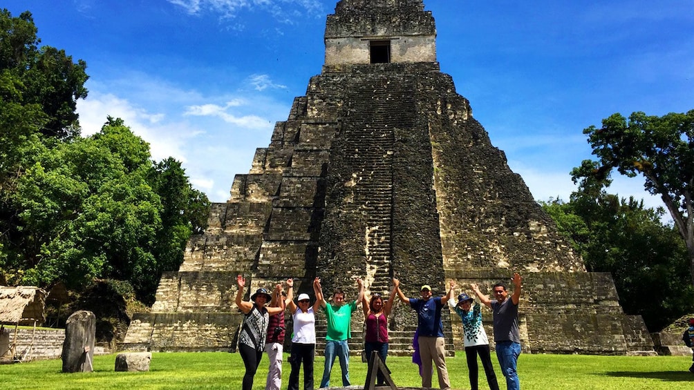 Group posing in front of tall temple in the ancient Mayan settlement of Tikal