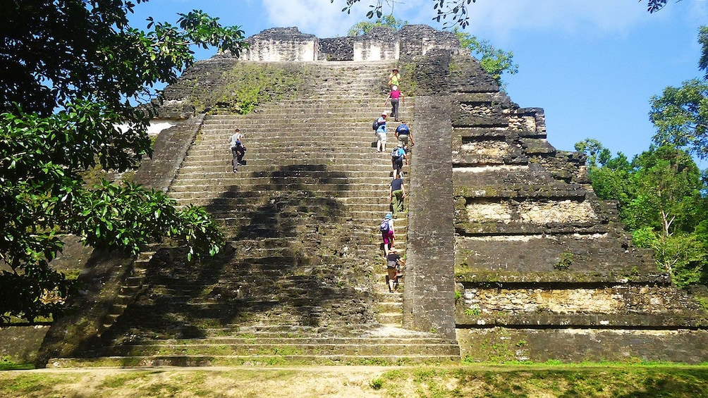 Tour group walkings up stairs of temple of ancient Mayan city of Tikal