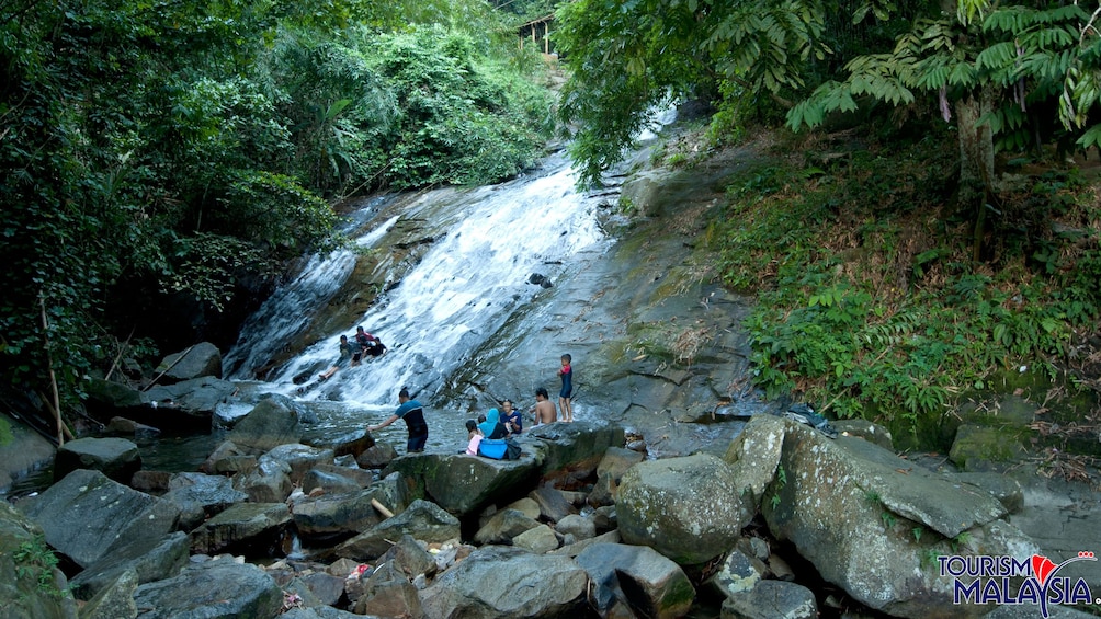 Show item 1 of 5. Group sliding down a rock waterfall at Templer's Park in Malaysia