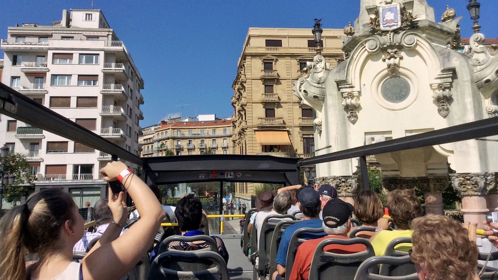 Passengers on the upper level of a hop-on hop-off bus tour in San Sebastian