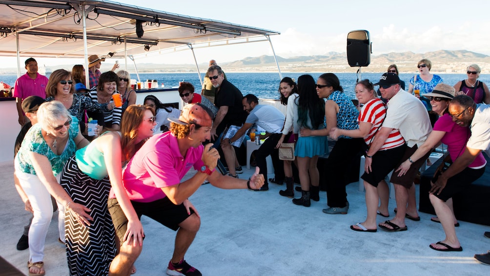 Passengers enjoying Congo line dancing aboard sunset cruise in Los Cabo