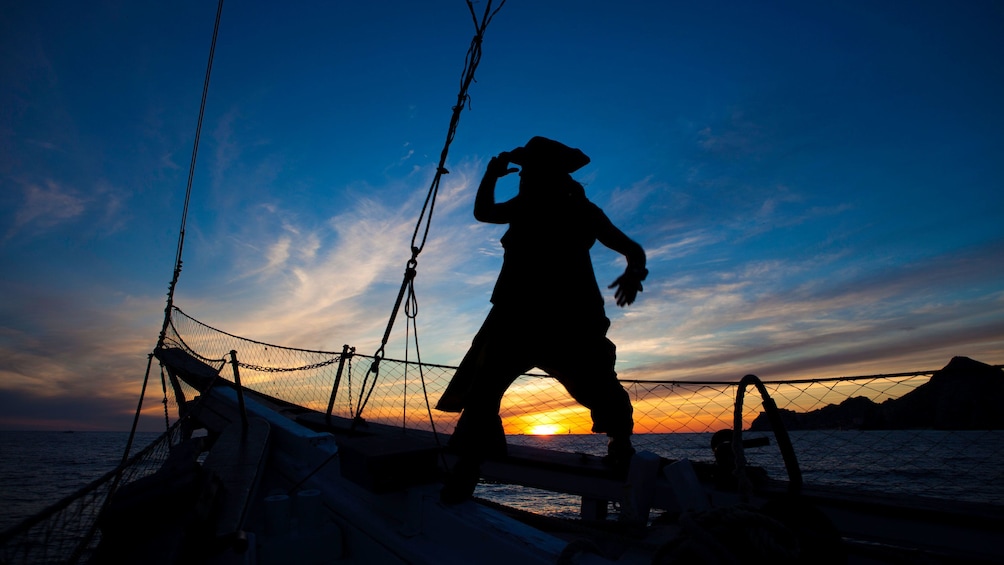 silhouette of pirate stands on bow of sailboat in Los Cabo