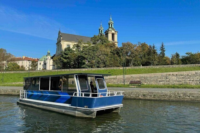 Group of tourists exploring the historic sights of Krakow from the deck of a modern catamaran. The dual-hulled vessel offers a stable and spacious platform for passengers as they snap photos.
