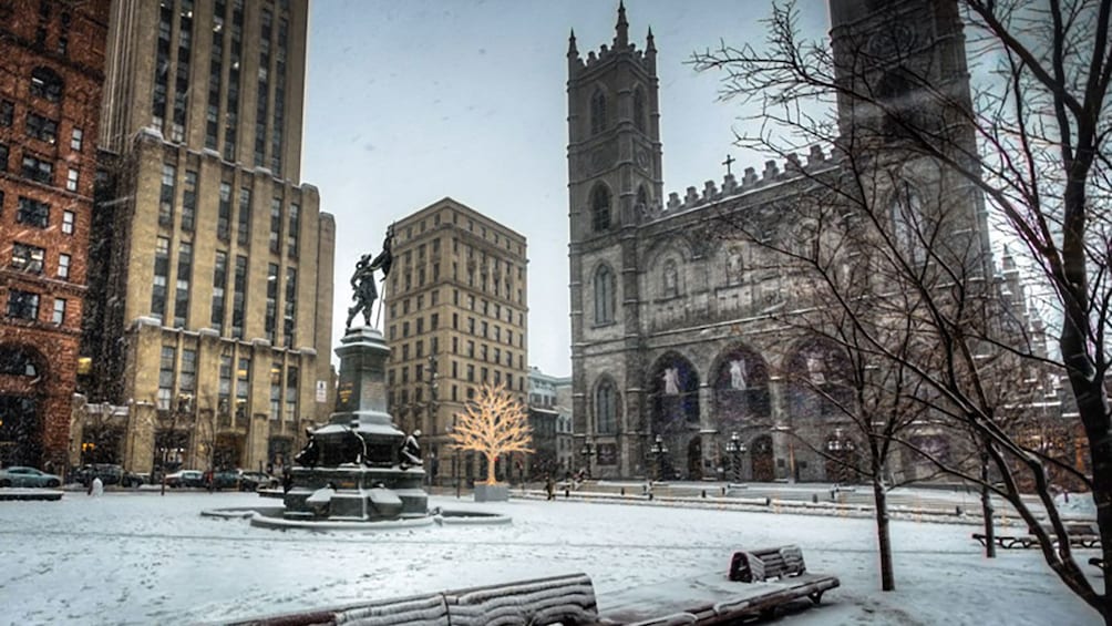 A square with a church and statue in Montreal during winter