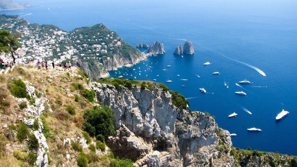 People on a grassy cliff looking down at the Amalfi Coast