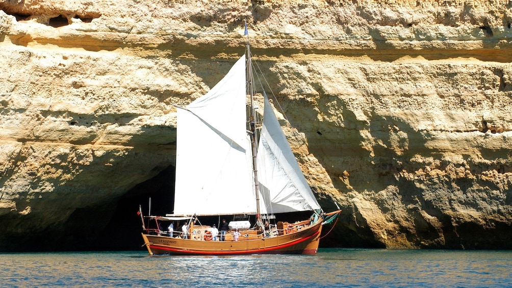 Sailboat passing a sea cave in Algarve