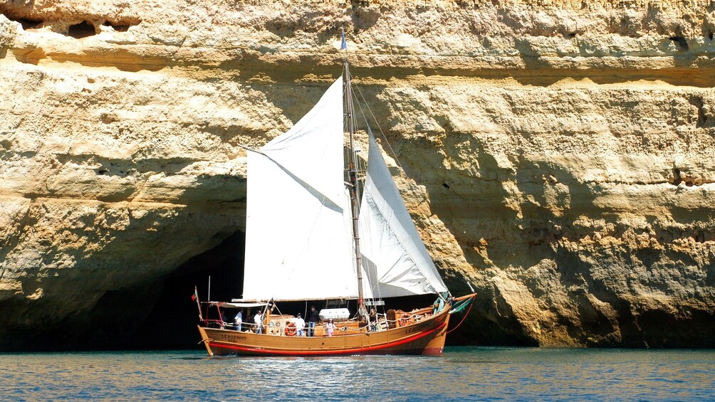 Sailboat passing a sea cave in Algarve