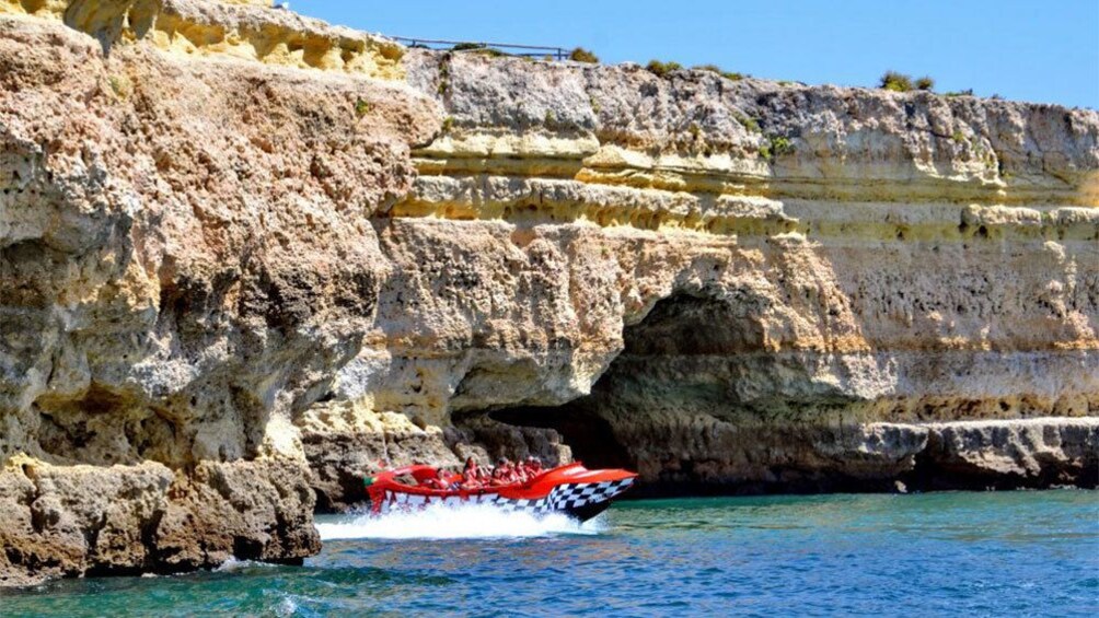 Jetboat near cliffs and sea cave along the coast of Algarve