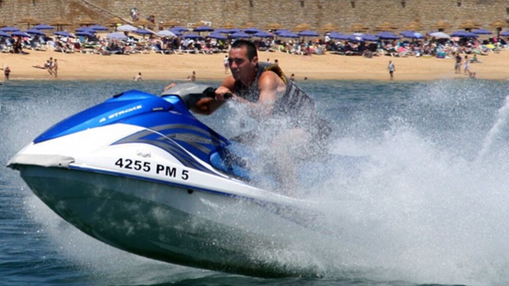 Jet Skiing man speeding through the water near a beach in Algarve