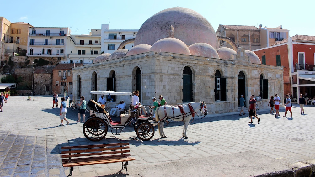 horse drawn carriage in front of a multi domed structure in Greece