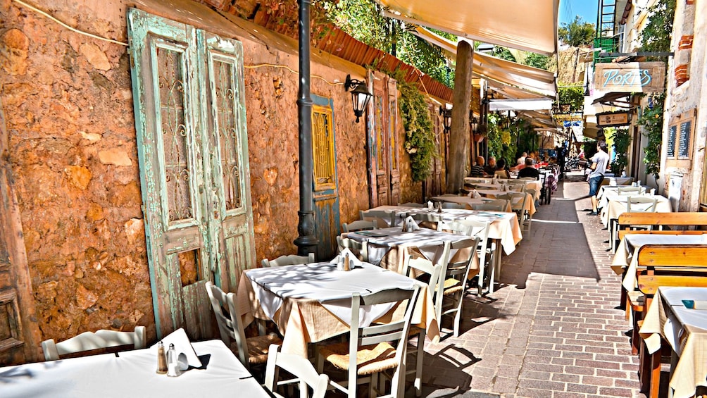 narrow brick road lined with dining tables outside in Greece