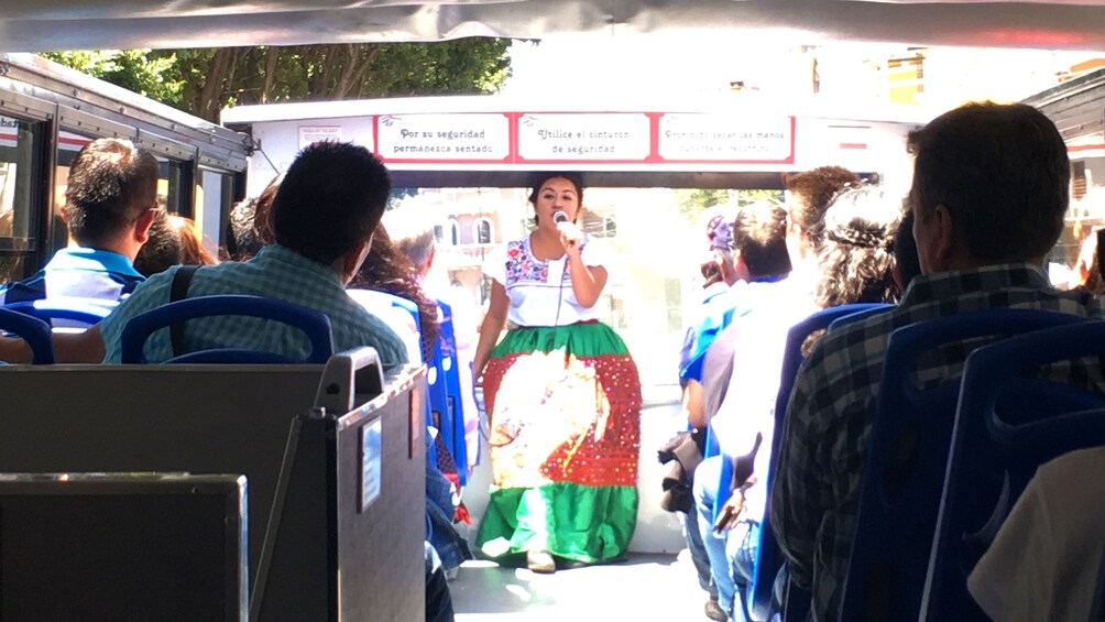 Tour guide talking to tourists on double decker tour bus in Puebla