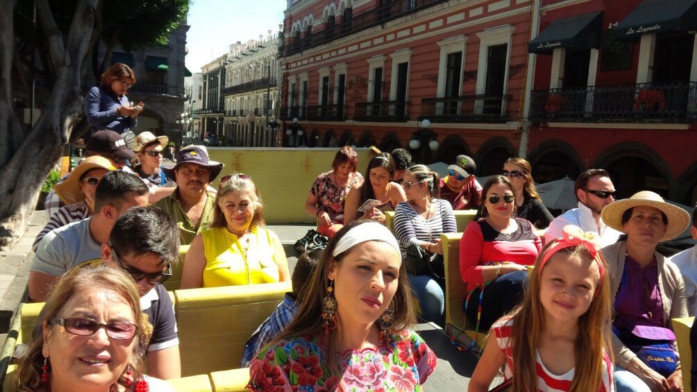 People riding on second level of double decker tour bus in Puebla