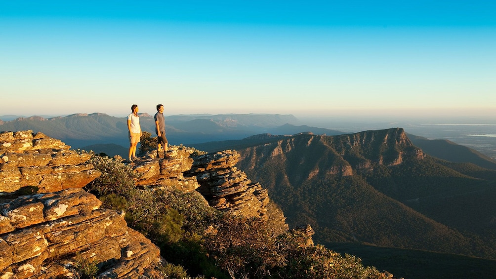 Show item 1 of 10. Two people standing on a rocky peak overlooking Grampians National Park