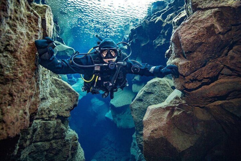 Scuba diver touching the tectonic plates in Silfra fissure