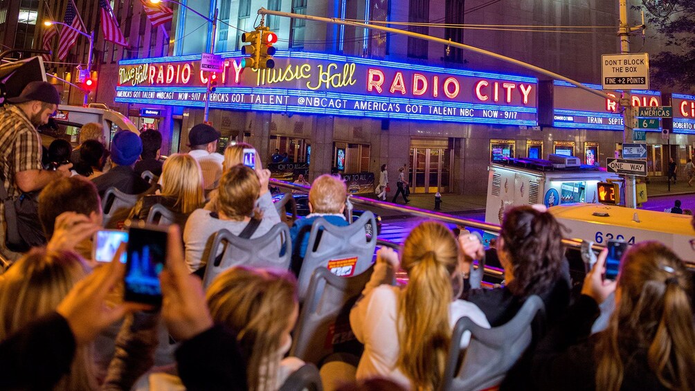 People on the upper level of a tour bus outside Radio City Music Hall in New York