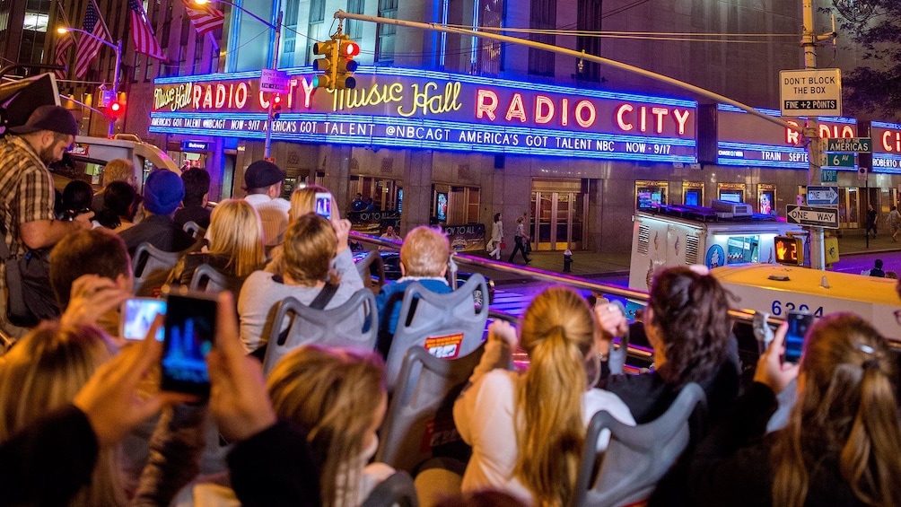 People on the upper level of a tour bus outside Radio City Music Hall in New York