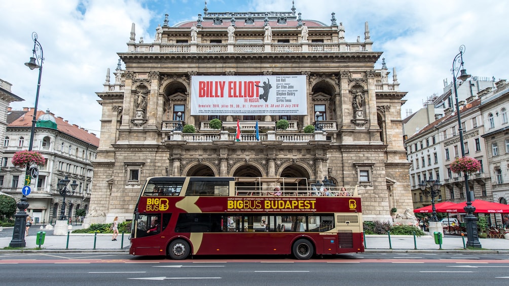 Hop on Hop off bus driving past a historical theater in Budapest