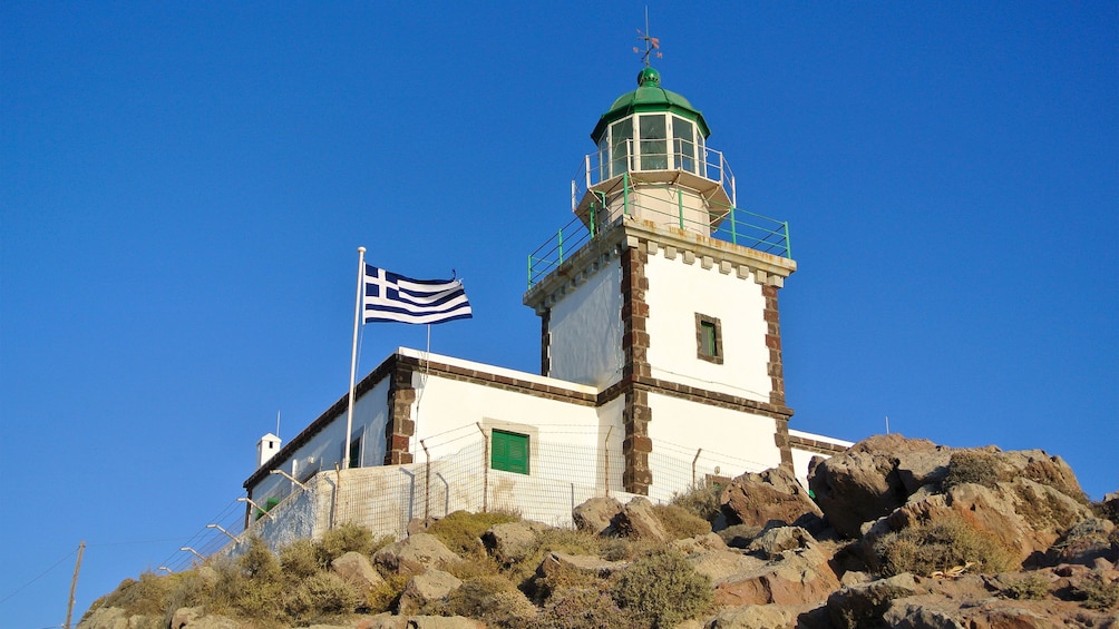 fenced lighthouse on top of the rocky hill in Santorini