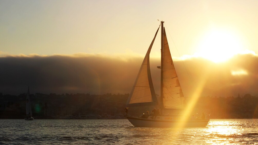 Sailboat traveling through calm waters at sunset in San Diego