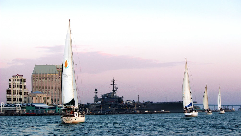Sailboats traveling past old aircraft carrier in San Diego