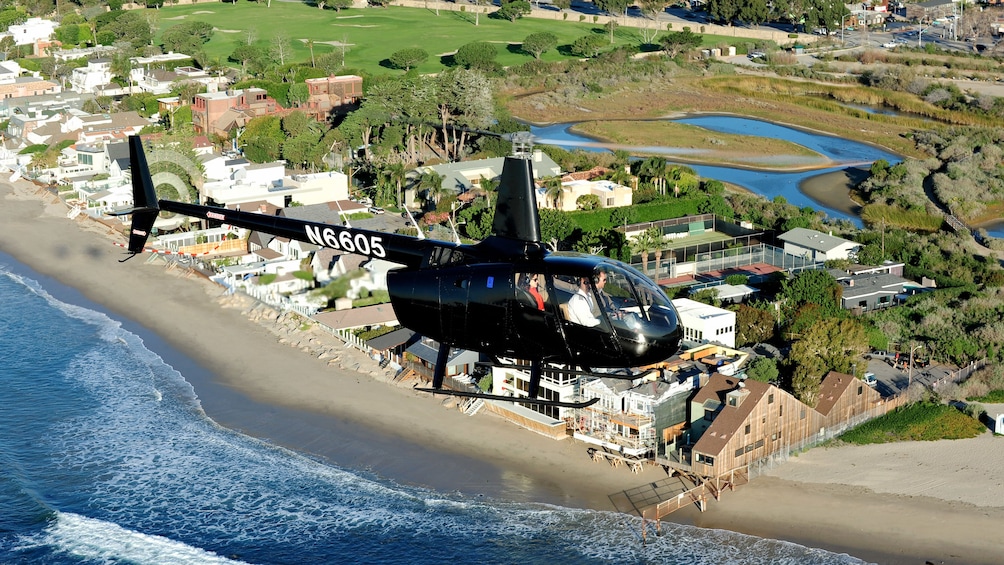 Aerial view of a black helicopter overlooking a body of water in Los Angeles 