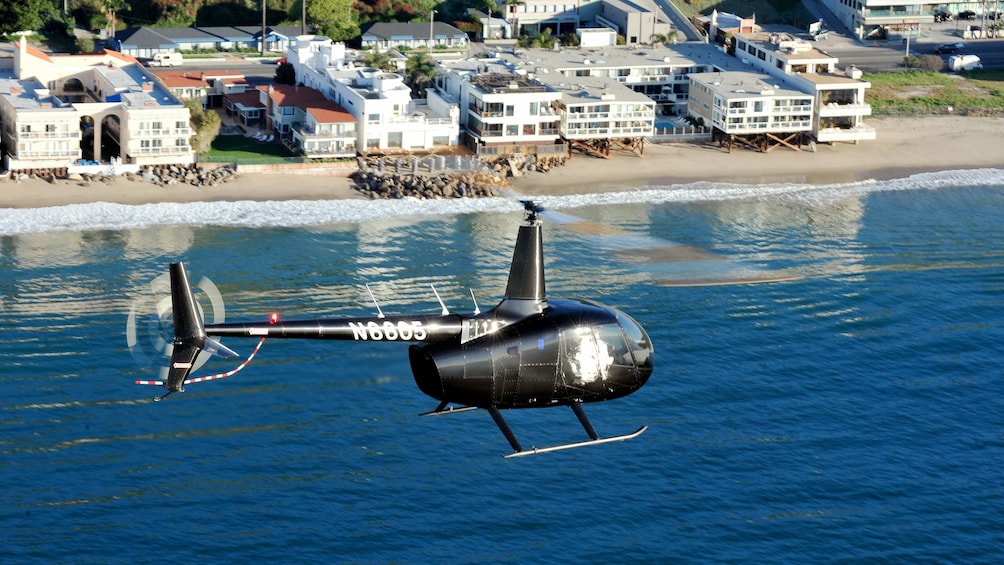 Black helicopter flying above Los Angeles water on a nice day 