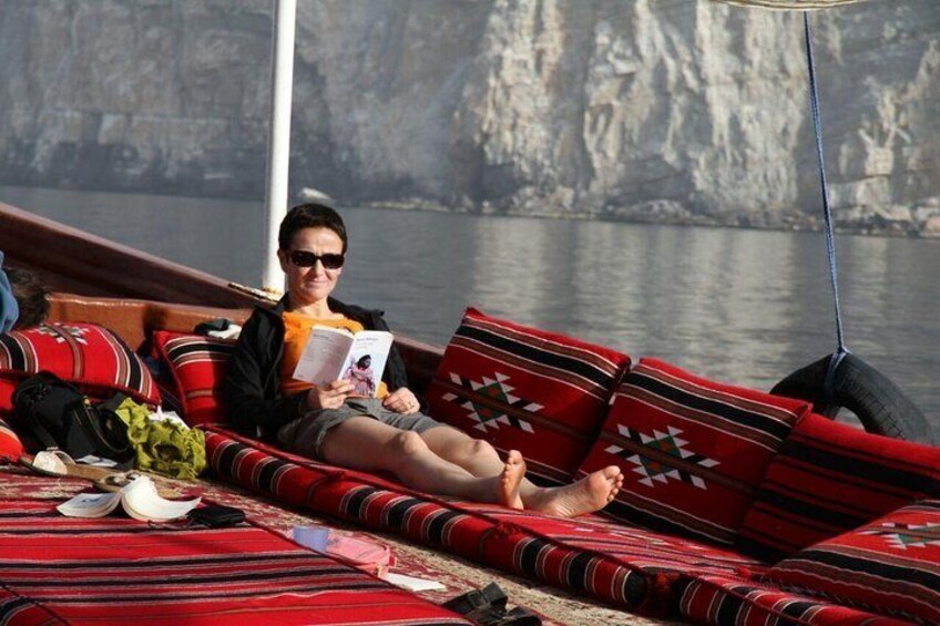 Guest relaxing on comfortable cushion looking at beautiful scenery of Musandam Fjords