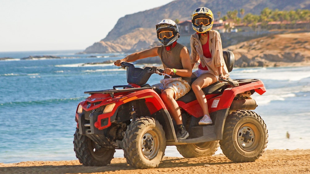 Couple riding an ATV at the beach in Los Cabos