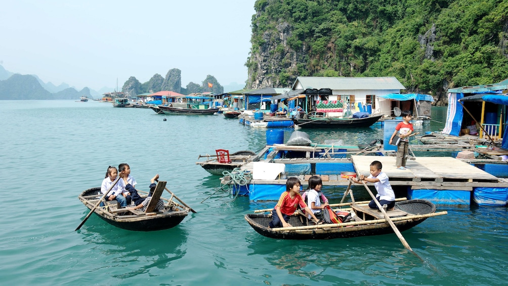 Children rowing small boats in Ha Long Bay