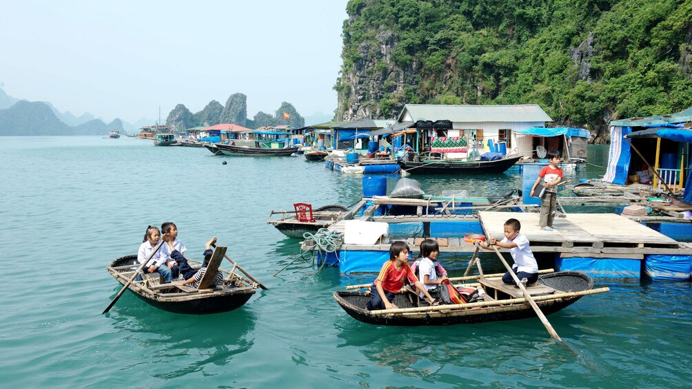 Children rowing small boats in Ha Long Bay