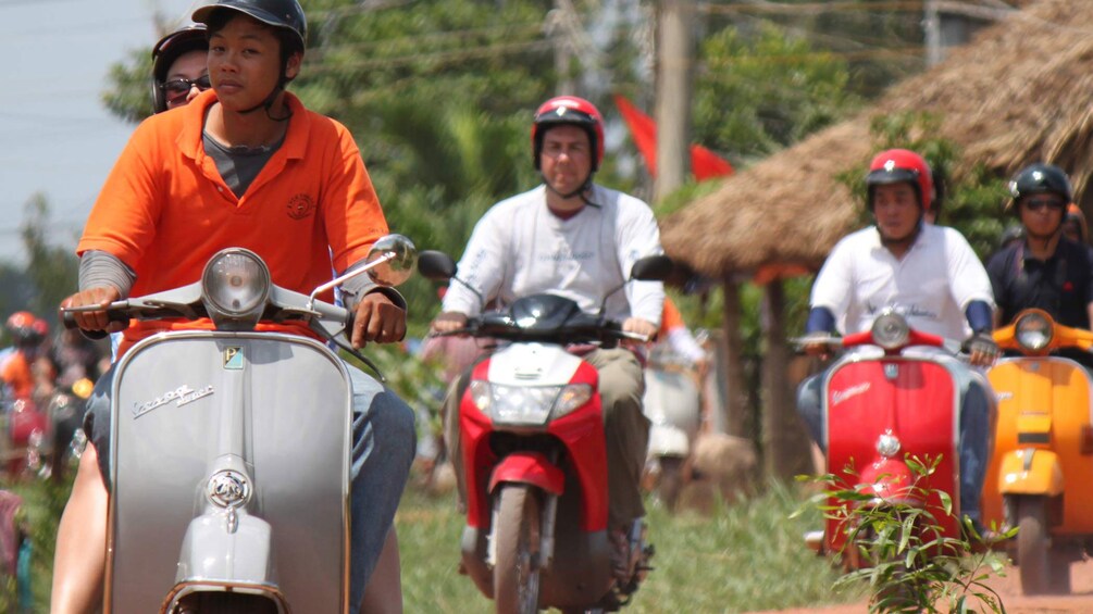 Tour group on scooters near a village in Mekong