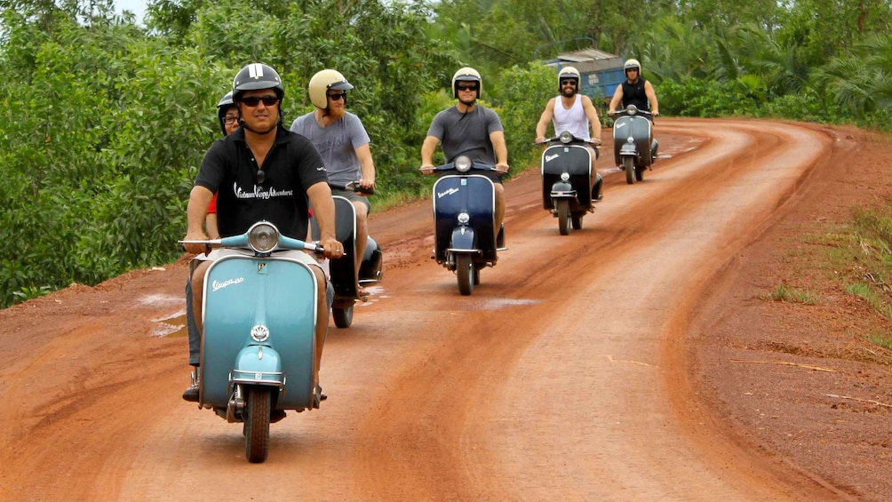 Scooter riding group on a dirt road in Mekong