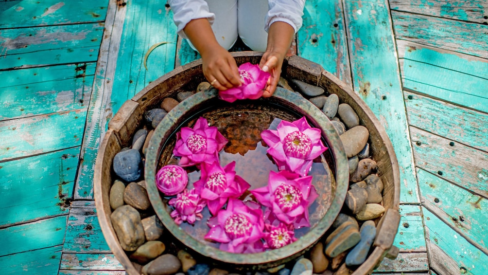Woman putting lotus flowers in a bowl of water at a spa in Siem Reap