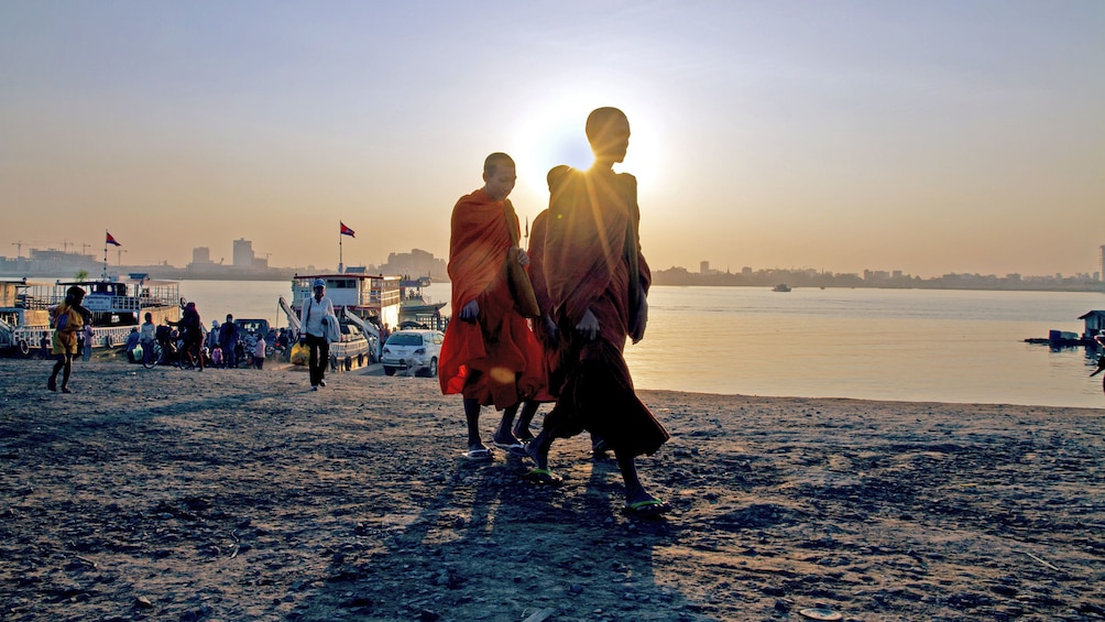 local monks walking on the beach sand during sunset in Cambodia