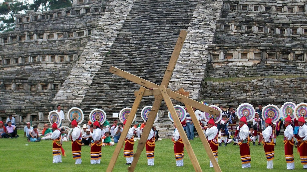 People in traditional attire performing a ceremony in front of the pyramid in Cuetzalan
