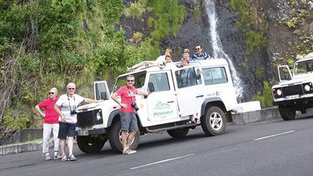 Tour group standing next to jeep with a waterfall in the background on Madeira Island