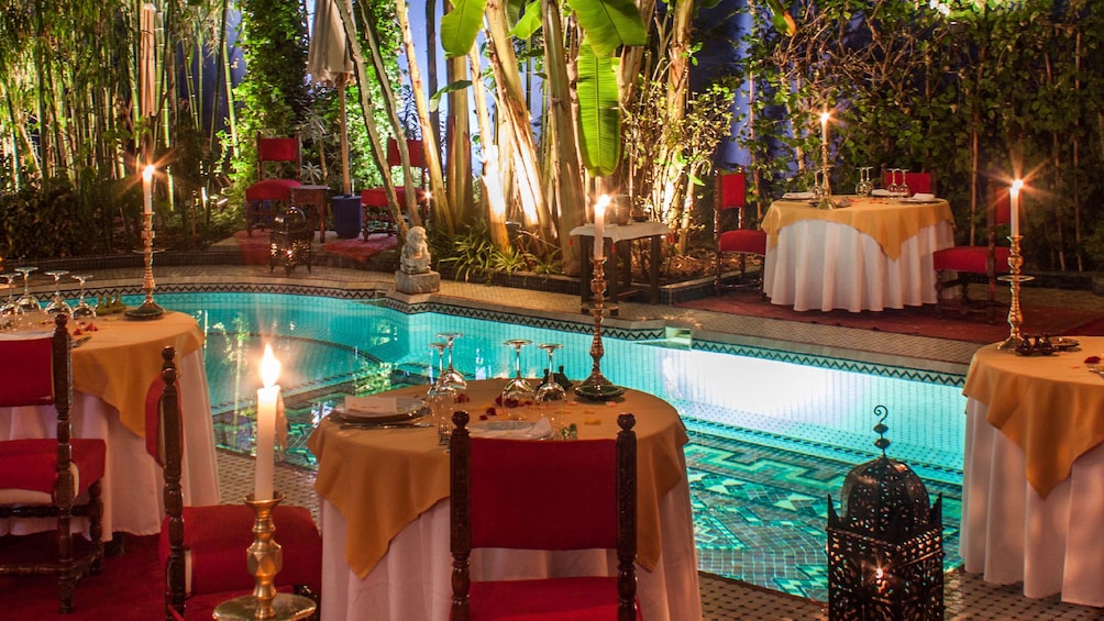Tables set surrounding a pool at Dar Moha in Marrakech