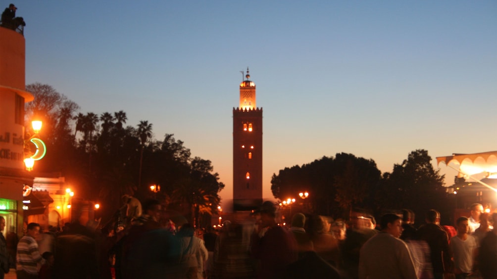 People walking down a bustling street in Marrakech at night