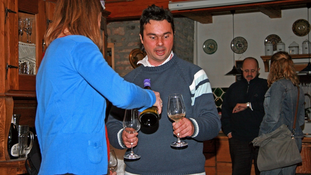 A woman pouring wine for a guest at a vineyard in Etyek